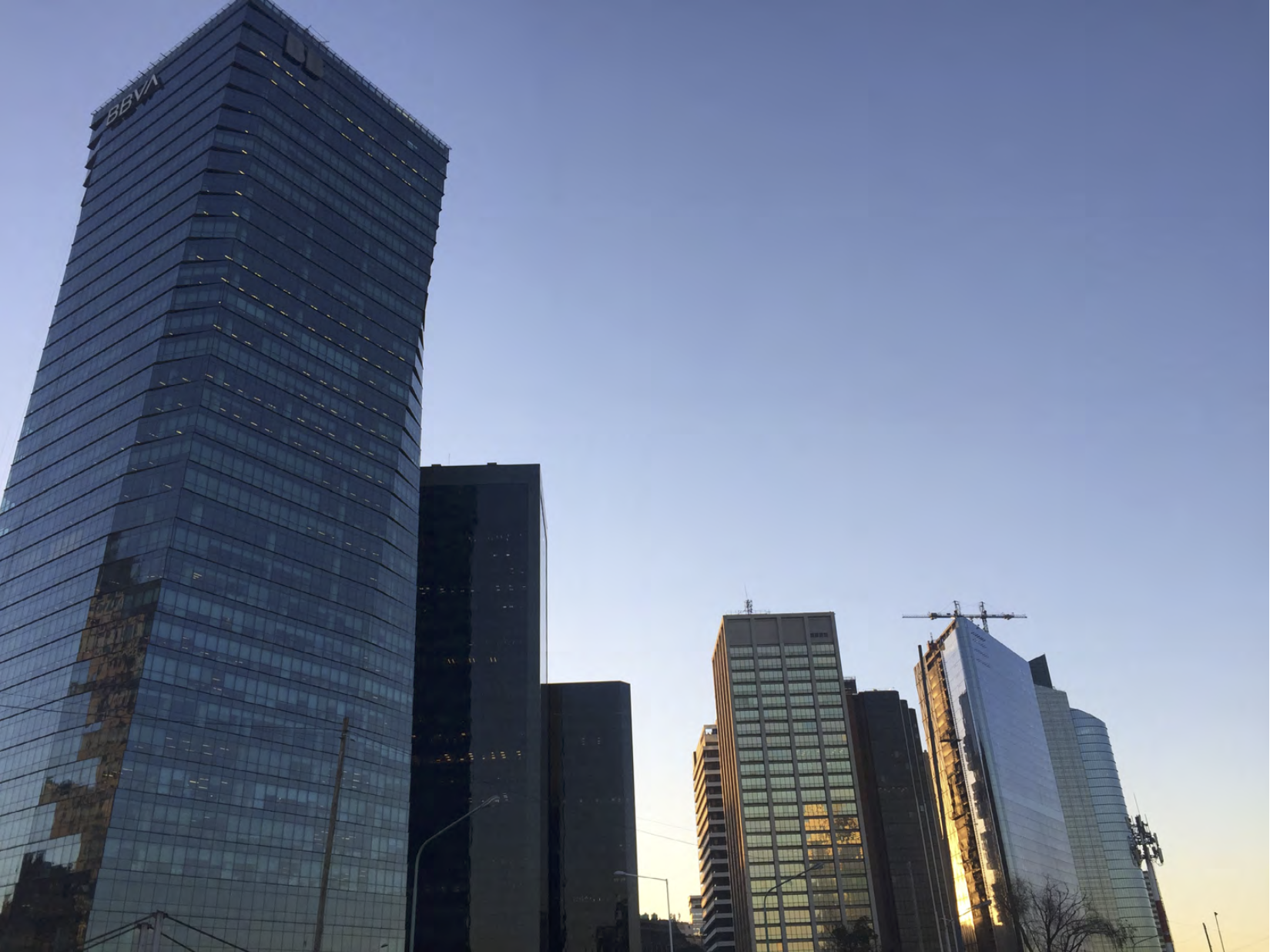 Street view of glass office towers at dusk, one marked with a bank logo